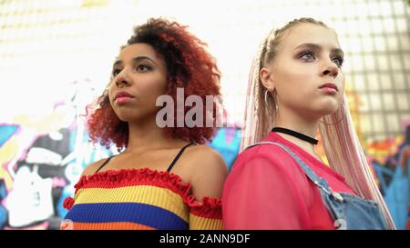 Two confident female teenagers standing back to back, new generation trends Stock Photo