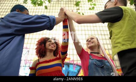 Young multiracial people joining hands, friendship greeting gesture, having fun Stock Photo