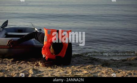 African-american man, pulling boat falling on shore, refugee survived shipwreck Stock Photo