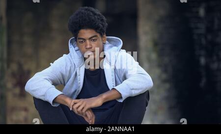 Pensive african american teenager with face wound sitting outdoors, bullying Stock Photo