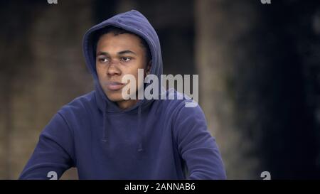 Pensive black millennial hoodie smoking cigarette outside, bad habit addiction Stock Photo