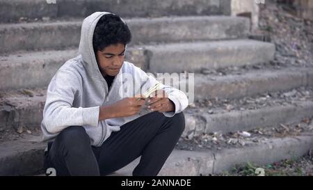 Disappointed black young man thinking of money sitting alone stairs, poverty Stock Photo