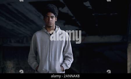 Desperate male teenager looking at camera standing abandoned building, ad Stock Photo