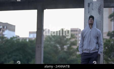Depressed african teenager hoodie thinking problem outdoors, negative experience Stock Photo