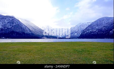 panorama of Hallstatt lake and green grass field outdoor dreamscape with snow mountain background in Austria in Austrian alps Stock Photo