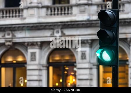 Green traffic lights for cars on a blurred buildings background - image Stock Photo