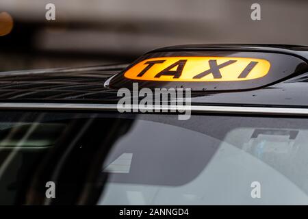 A british london black taxi cab sign with defocused  background - image Stock Photo