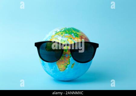 Tourism, ecology, vacation and globalism concept. Globe in sunglasses on a blue background banner. Minimal creative. Stock Photo
