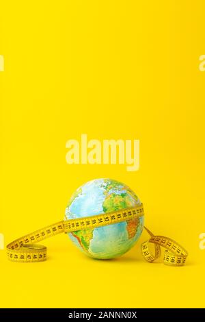 Big date, research, study, distances, measurements and size concept. Earth globe and measuring tape on a yellow background. Minimal, copy space. Stock Photo