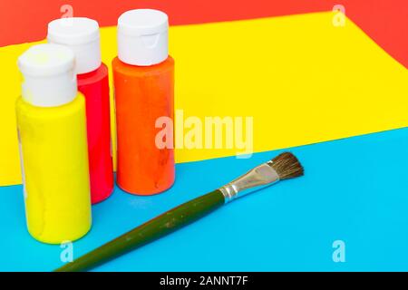 Red, yellow, and blue art flatlay concept with green paintbrushes and bright coloured paint illustrating creativity, inspiration, and artistic express Stock Photo