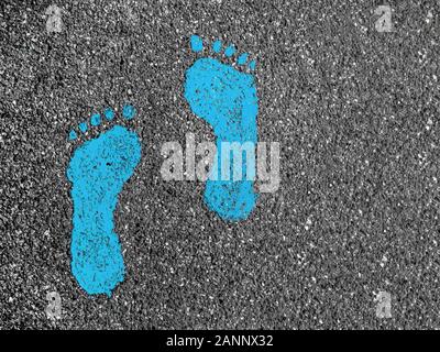 Green footprint signs on an asphalt road for pedestrian. Symbol of walkway. Stock Photo