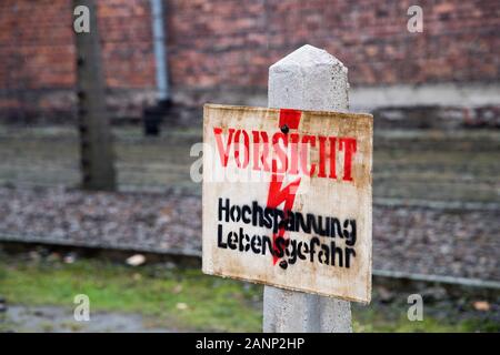 Vorsicht Hochsppannung Lebensgefahr sign (Caution, risk of electric shock sign) and barbed wire fence in Nazi German Konzentrationslager Auschwitz I S Stock Photo
