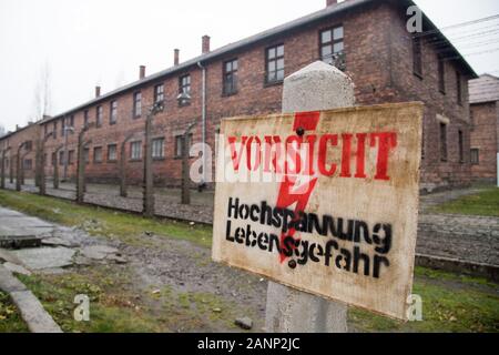 Vorsicht Hochsppannung Lebensgefahr sign (Caution, risk of electric shock sign) and barbed wire fence in Nazi German Konzentrationslager Auschwitz I S Stock Photo