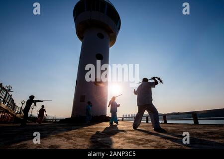 Tai Chi at dawn in the Chinese city of Zhaoqing - popular amongst locals, who congregate as the sun rises.  Here, older people practice the art. Stock Photo