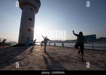 Tai Chi at dawn in the Chinese city of Zhaoqing - popular amongst locals, who congregate as the sun rises.  Here, older people practice the art. Stock Photo