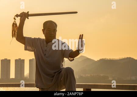 Tai Chi at dawn in the Chinese city of Zhaoqing - popular amongst locals, who congregate as the sun rises.  Here, older people practice the art. Stock Photo