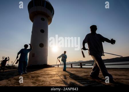 Tai Chi at dawn in the Chinese city of Zhaoqing - popular amongst locals, who congregate as the sun rises.  Here, older people practice the art. Stock Photo