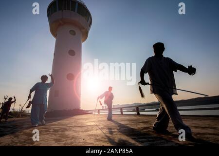 Tai Chi at dawn in the Chinese city of Zhaoqing - popular amongst locals, who congregate as the sun rises.  Here, older people practice the art. Stock Photo