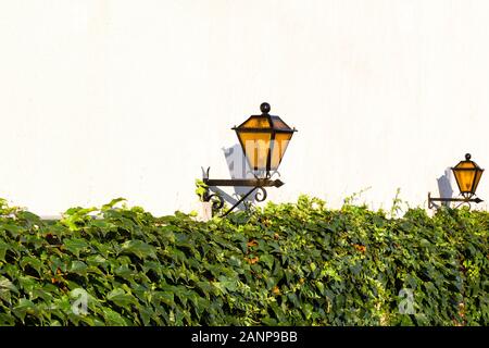 Street lights on a white plastered wall on a sunny day Stock Photo