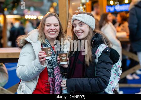 Visitors at the Edinburgh Christmas Market in East Princes Street Gardens, with the big wheel and Scott Monument at dusk, Edinburgh, Scotland, UK Stock Photo