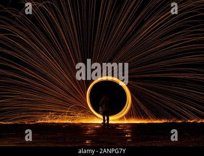 Steel wool painting with light in darkness spark effect and reflections on wet ground Stock Photo