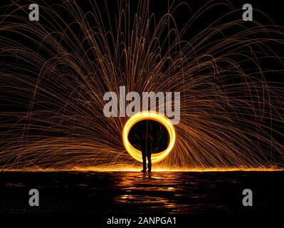 Steel wool painting with light in darkness spark effect and reflections on wet ground Stock Photo