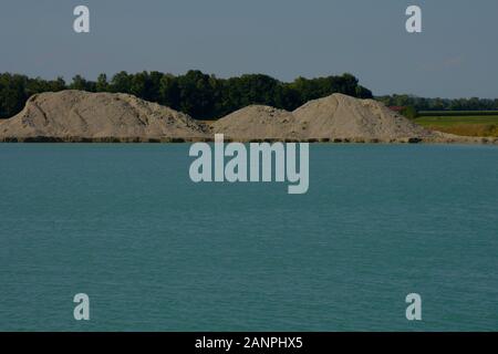 excavation lake with big pile of sand and gravel after dig up, rural idyll on a quarry pond in bavaria Stock Photo