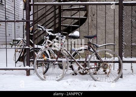 Bicycles locked to a fence, covered in snow during a winter snowfall in Montreal on the Plateau area Stock Photo
