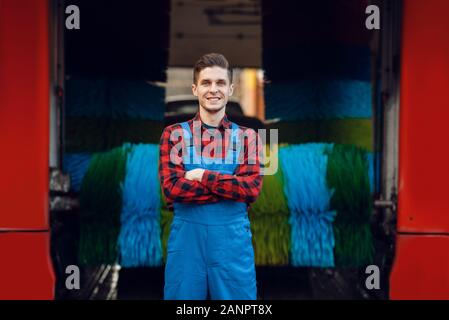 Male washer in uniform on automatic car wash Stock Photo