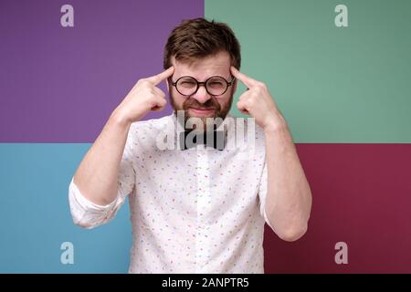 Bearded man in round glasses is trying to remember something, he is trying very hard to gather his thoughts. Stock Photo
