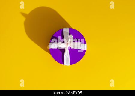 a violet gift box on yellow background. Stock Photo