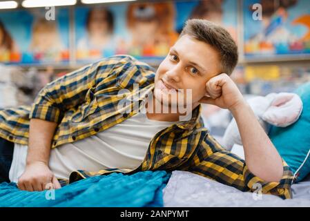Young man lying on the bed in bedding store Stock Photo