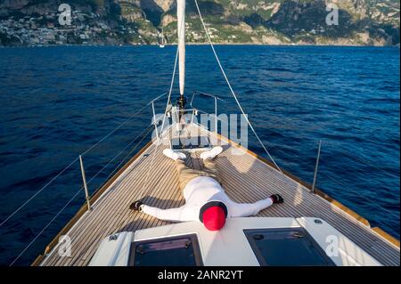 Man relaxing at teak deck of luxury sailing yacht. Amalfi coast, Italy. Stock Photo