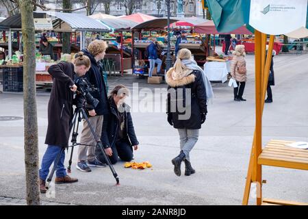 One camera crew filming scene in Ljubljana Maket with actor on knees by smashed pumpkin while girl walks away Stock Photo