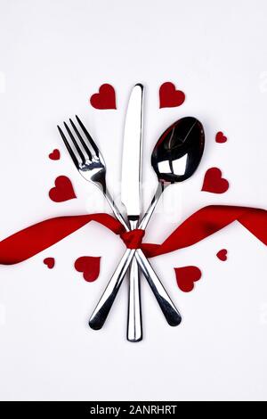 Cutlery set tied with silk ribbon and hearts on white background Valentine day dinner concept Stock Photo