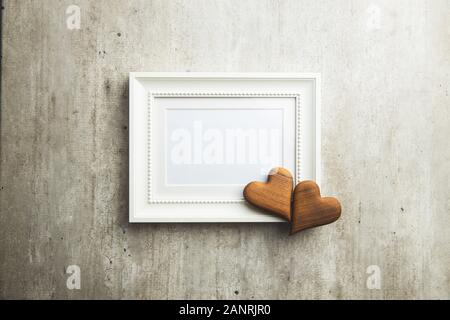 Love Valentine's Day concept. Blank picture frame and wooden heart. Top view. Stock Photo
