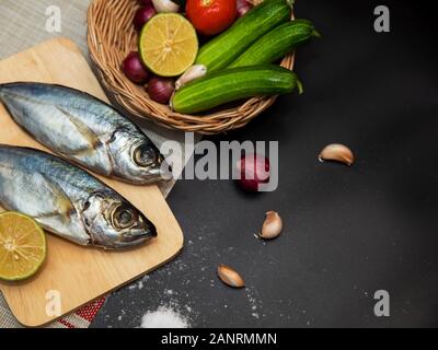 Fresh mackerel and ingredients for cooking. Spices and vegetables on black table Top view with copy space Stock Photo