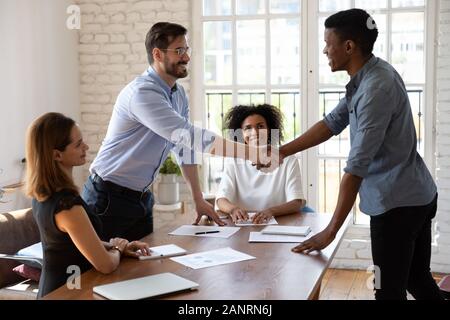 Happy diverse business partners shaking hands, making agreement Stock Photo
