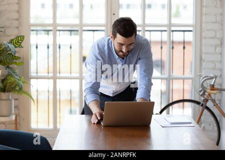 Confident businessman wearing glasses using laptop in modern office Stock Photo