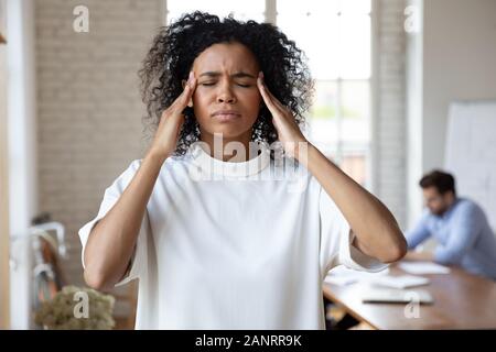 Head shot stressed African American businesswoman feeling headache, touching temples Stock Photo