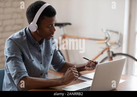 African American businessman wearing headset using laptop, working online Stock Photo