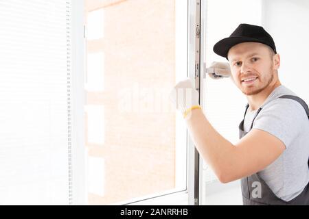 Construction worker man uses screwdriver to screw handle install plastic white upvc windows in house Stock Photo