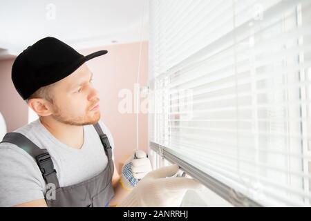 Construction worker man install blinds on plastic white upvc windows in house Stock Photo