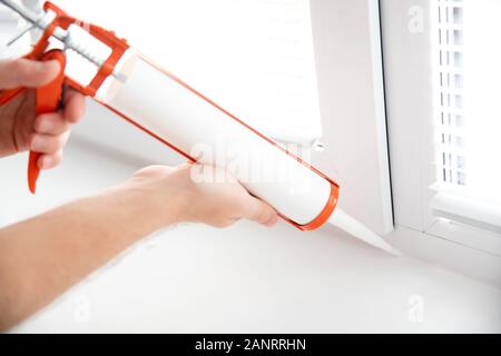 Construction worker use gun silicone tube for repairing and installing window in house Stock Photo