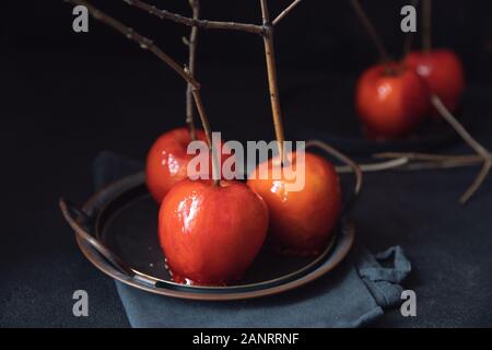 Dessert Sugar red apples in caramel on plate candy, dark background Stock Photo