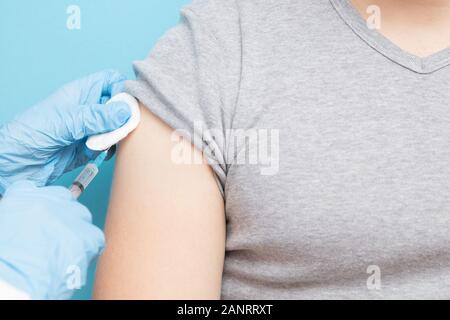 Doctor gives man syringe with vaccine in shoulder for colds and flu. Concept injection fever, blue color Stock Photo
