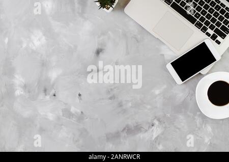 White smartphone with black blank screen on office desk with laptop and cup of coffee on gray concrete. Mock up of phone. Business or education concep Stock Photo
