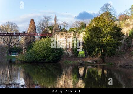 The Parc des Buttes-Chaumont, the red bridge and the lake in winter 2020, fifth-largest public park in Paris, FRANCE. Stock Photo