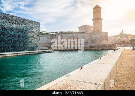 Fort Saint-Jean guarding the entrance of old port with Fanal tower and dramatic light in Marseille France Stock Photo