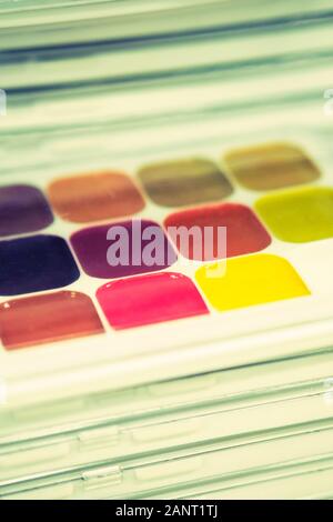 Stack of packages with different colors - watercolor for the artist. Toned. Vertical. Close up. Stock Photo